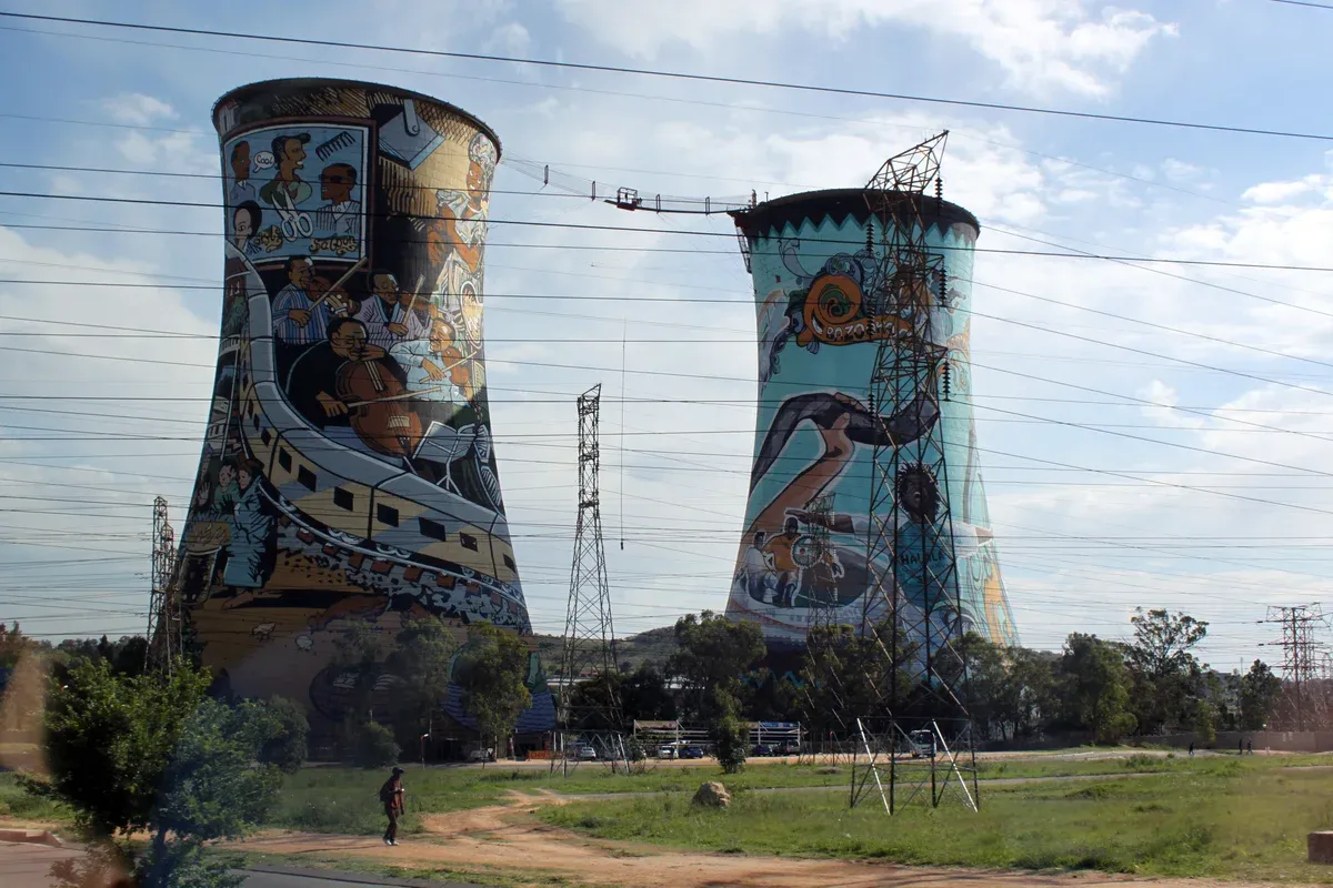 The two Orlando cooling towers standing over Soweto, painted sides facing the street