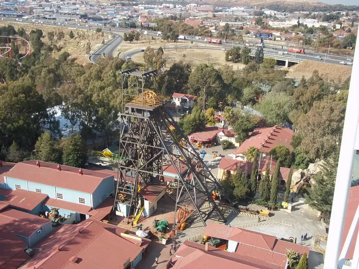 The mine headgear at Gold Reef City seen from above, next to the theme park rides